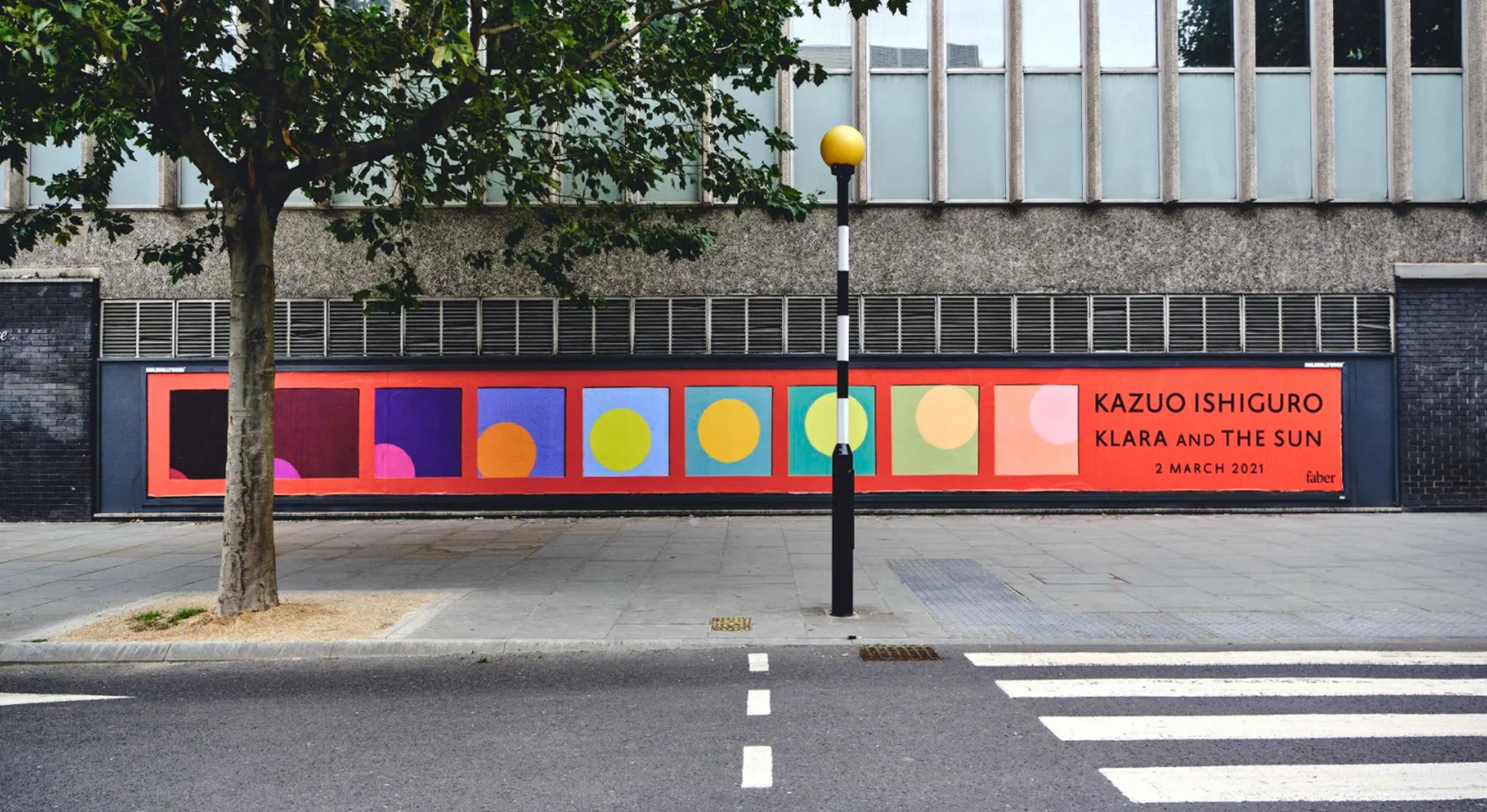 Faber's publication-reveal hoarding on a London street: the endpaper panels enlarged into a single row on red, announcing Klara and the Sun, 2 March 2021